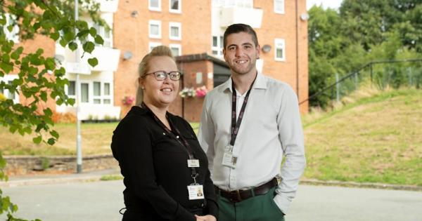 two resident officers smiling outside a low rise block of apartments