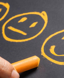 three ai generated smiley faces drawn on a blackboard by a hand holding chalk