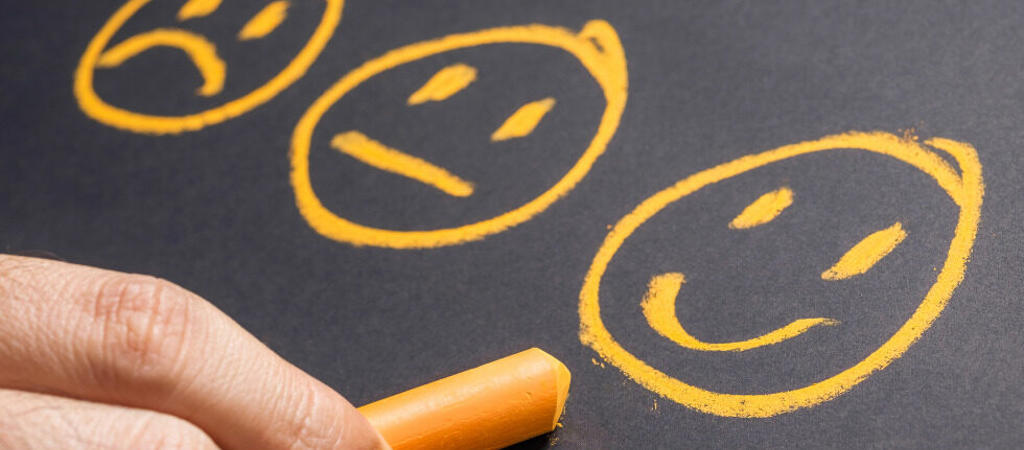 three ai generated smiley faces drawn on a blackboard by a hand holding chalk