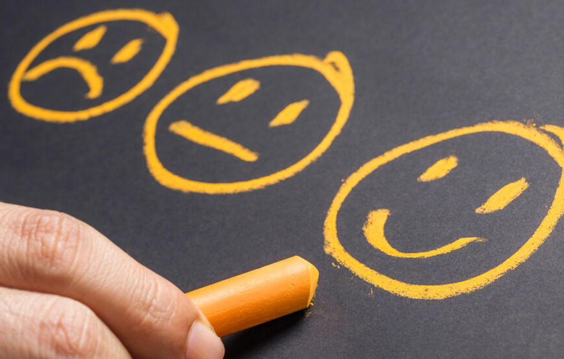 three ai generated smiley faces drawn on a blackboard by a hand holding chalk