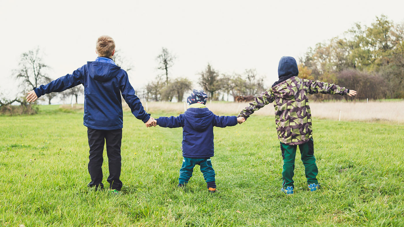 childcare stock photo 3 kids all holding hands in a field