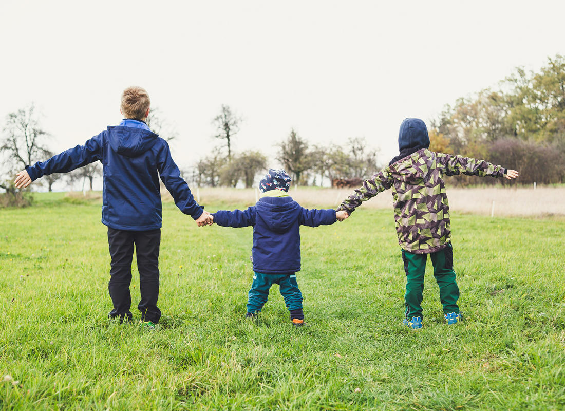 childcare stock photo 3 kids all holding hands in a field
