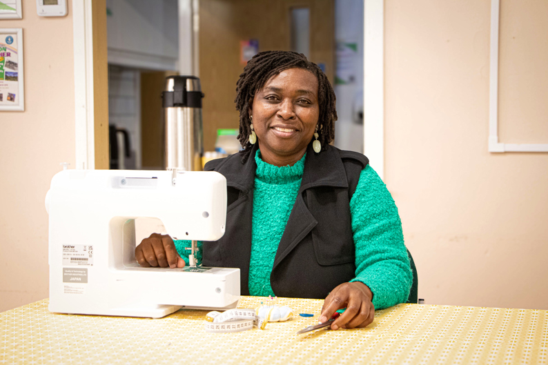 valery sitting in front of a sewing machine smiling at the camera