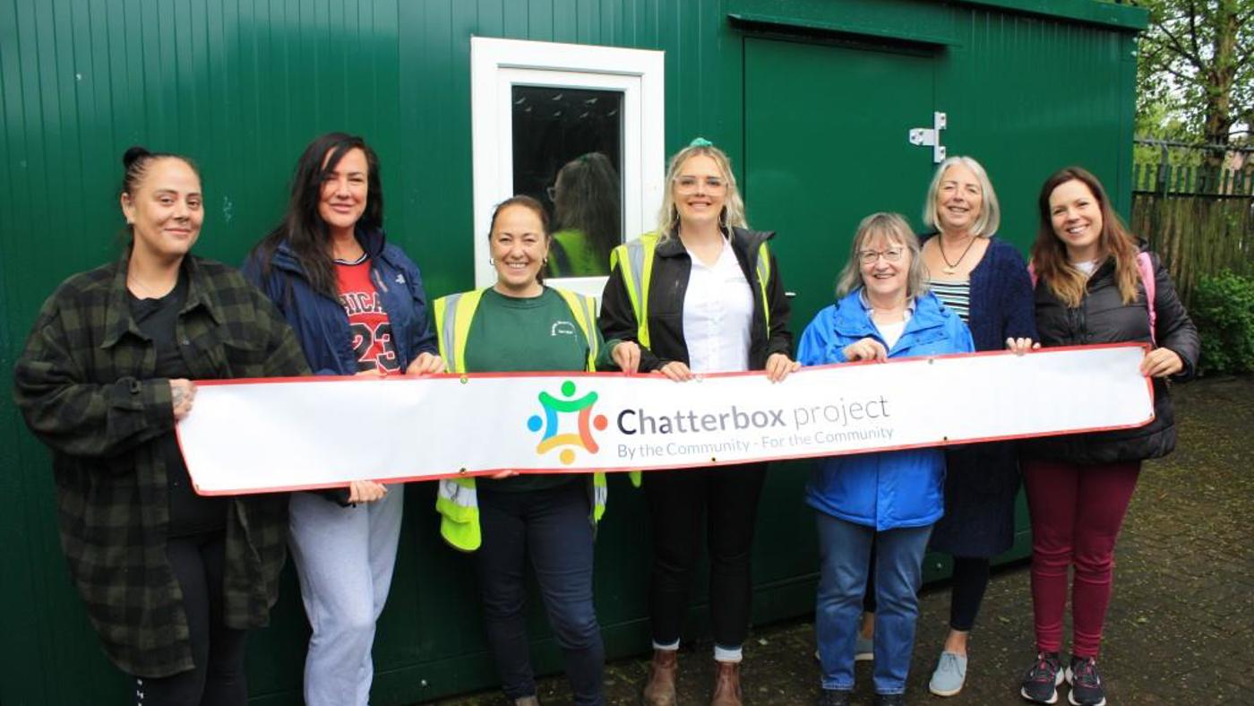 The Team At The Chatterbox Project In Front Of The Storage Unit With Some Of The Emanuel Whittaker Team Holding A Banner Saying Chatterbox