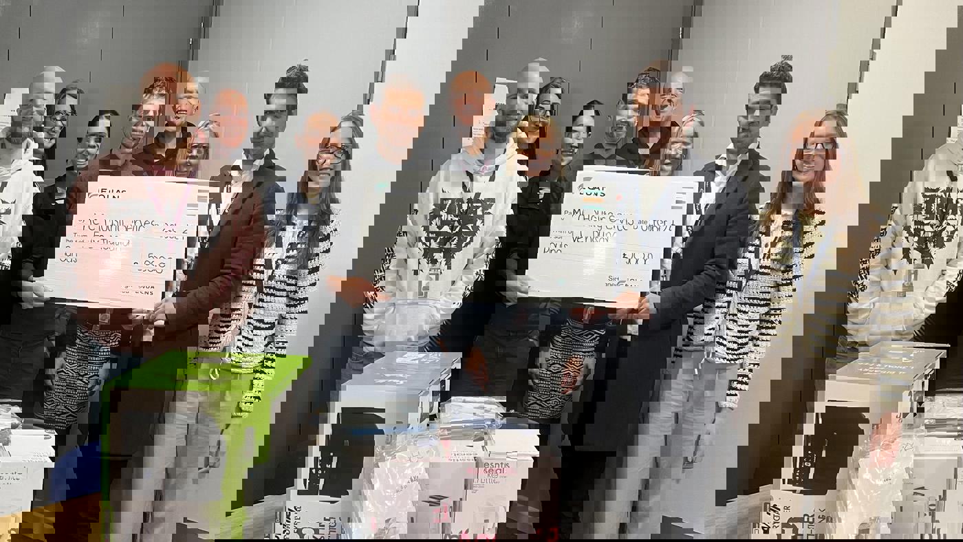 group of staff and equans stood with a large novelty cheque