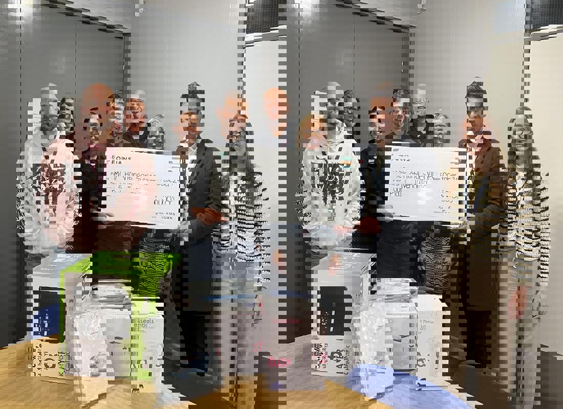 group of staff and equans stood with a large novelty cheque