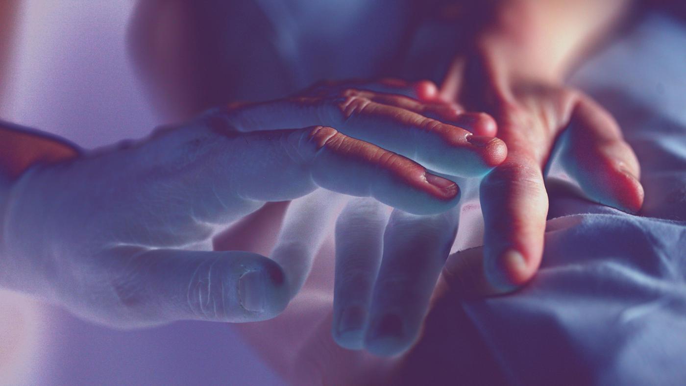 bereavement stock photo over exposed image of two hands touching