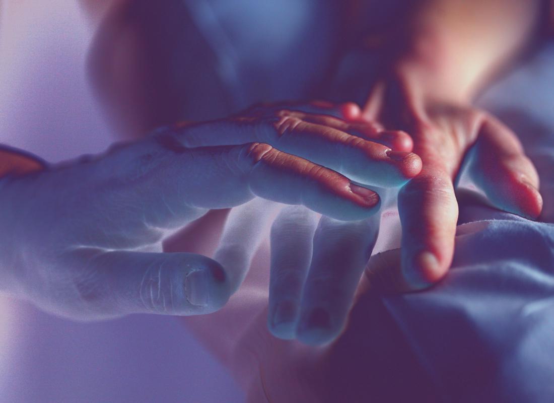bereavement stock photo over exposed image of two hands touching