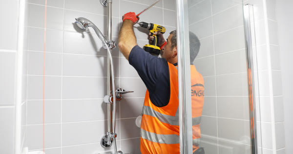 an engie engineer fitting a shower with an electric drill